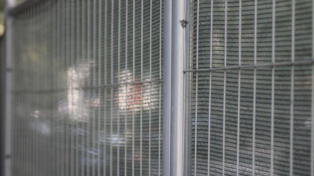Close view of a fence panel on a construction site secured with anti climb fencing and privacy screening during early spring